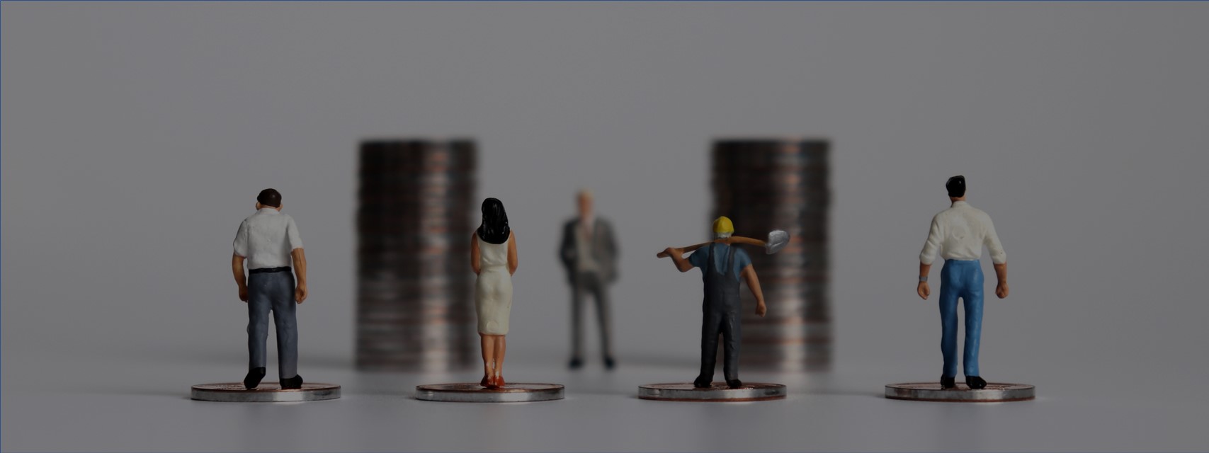 Miniature people with piles of coins to illustrate the concept of wealth creation for all workers.