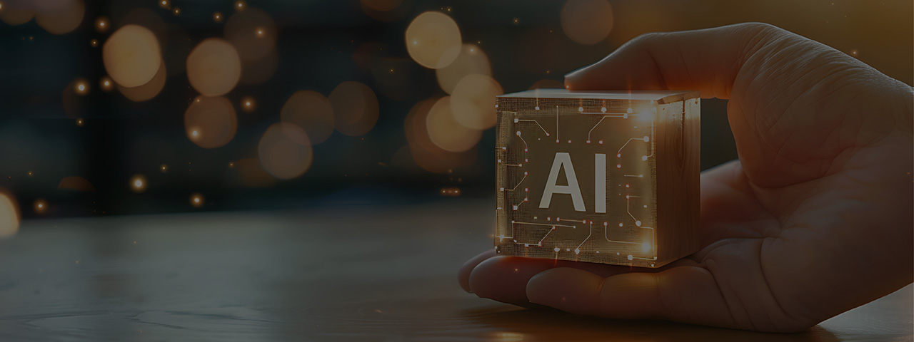 Image of a hand holding a block with the letters "AI" imprinted on it and lines that are reminiscent of computer circuitry